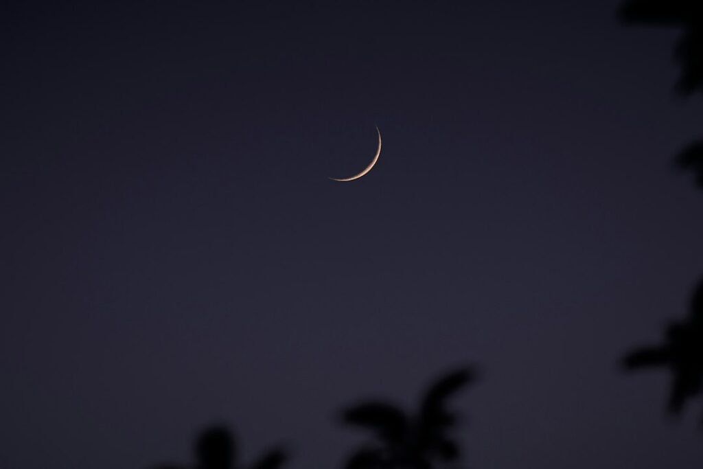 A crescent Moon in a cultural landscape, representing festivals whose dates move through a lunar calendar