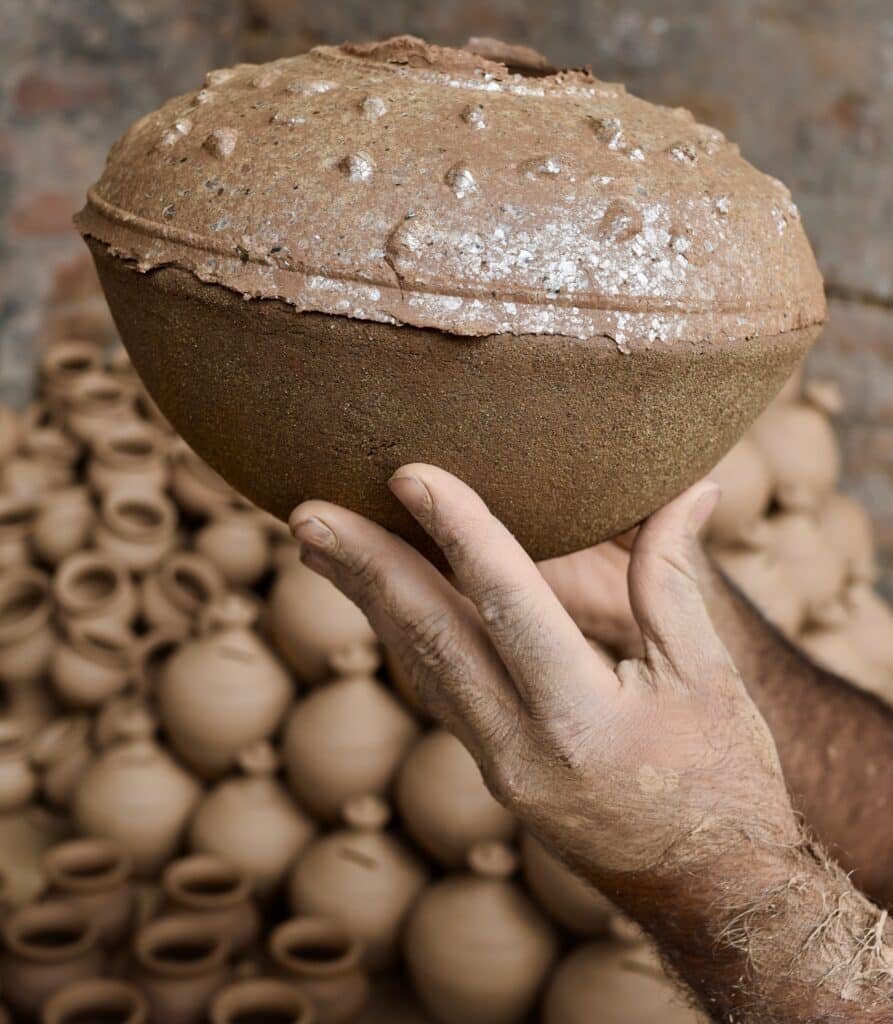 Traditional handmade earthen pot held by a potter in northern India